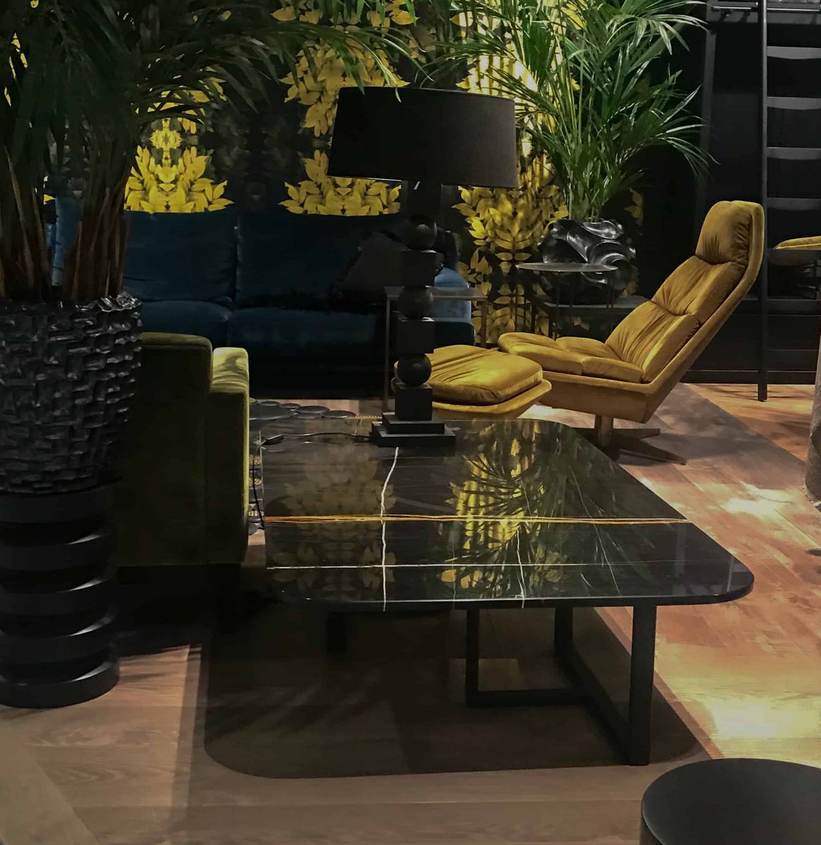 Salontafel met zwart marmeren blad tussen gele fauteuils