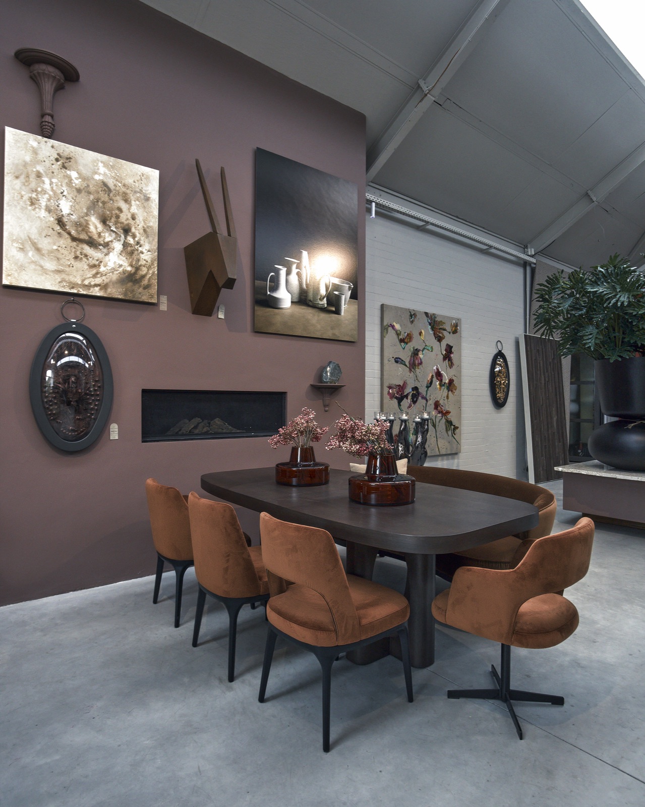 Eettafel met cognac stoelen onder een hoog dak in de showroom