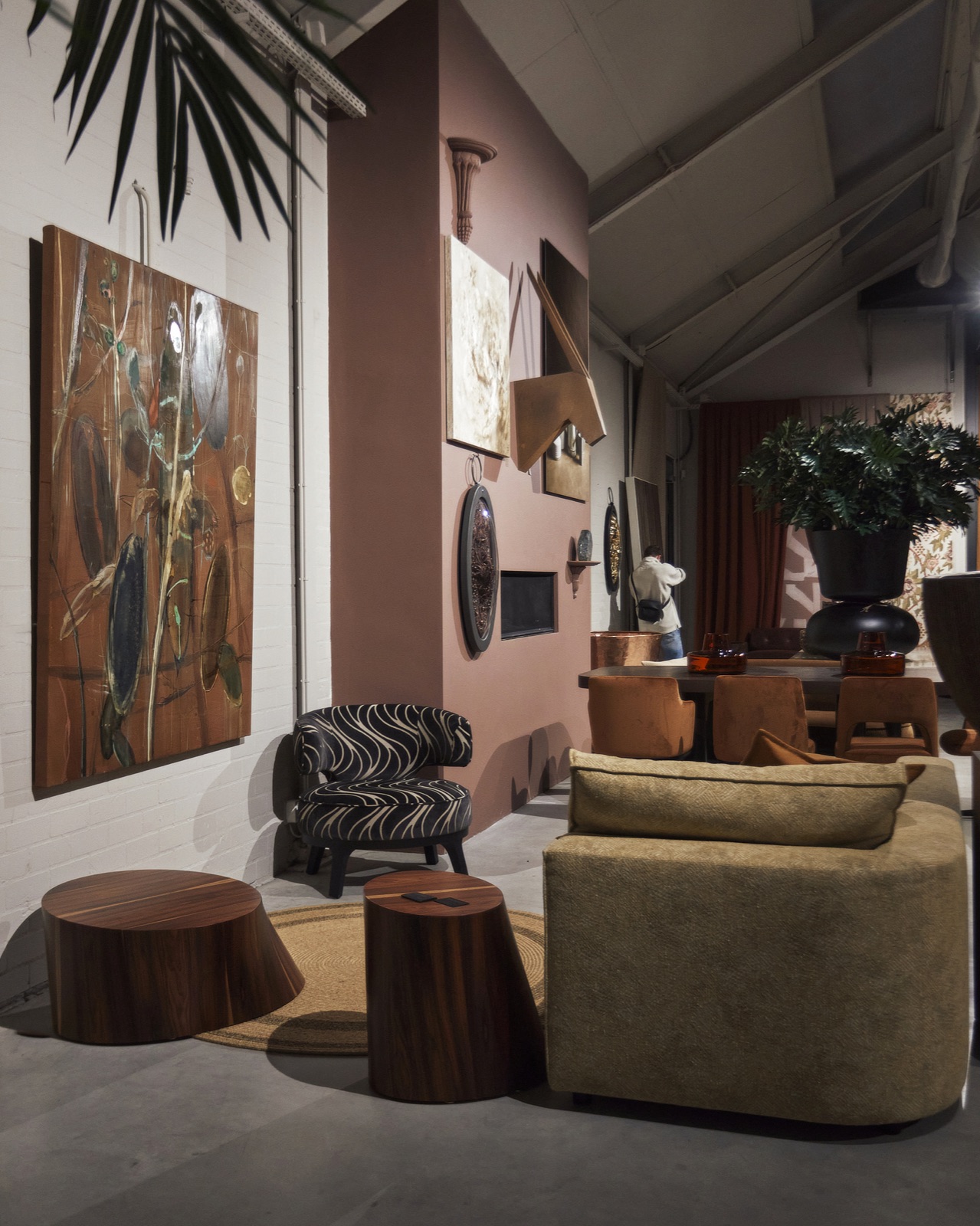 Zithoek in de showroom met een roze wand, een zebrastoel en houten bijzettafels