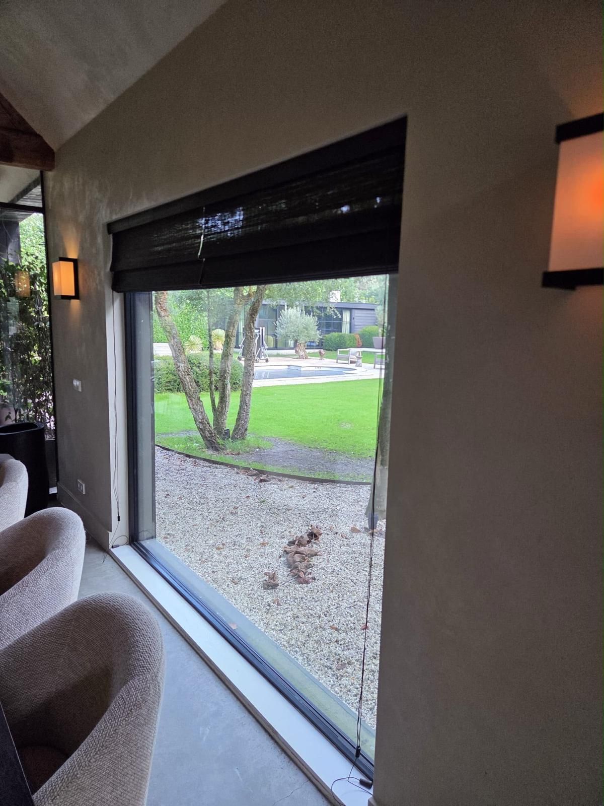 Geweven houten blind voor een groot raam in een woonkamer